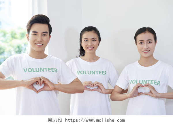 做爱心手势的年轻志愿者亚洲年轻人的肖像，他们是志愿者协会的成员，站在他们手中做一个心脏的形状